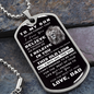 Military dog tag style necklace with a message to a son from father.  Includes a picture of an old lion.  The necklace is laying against a stone background.