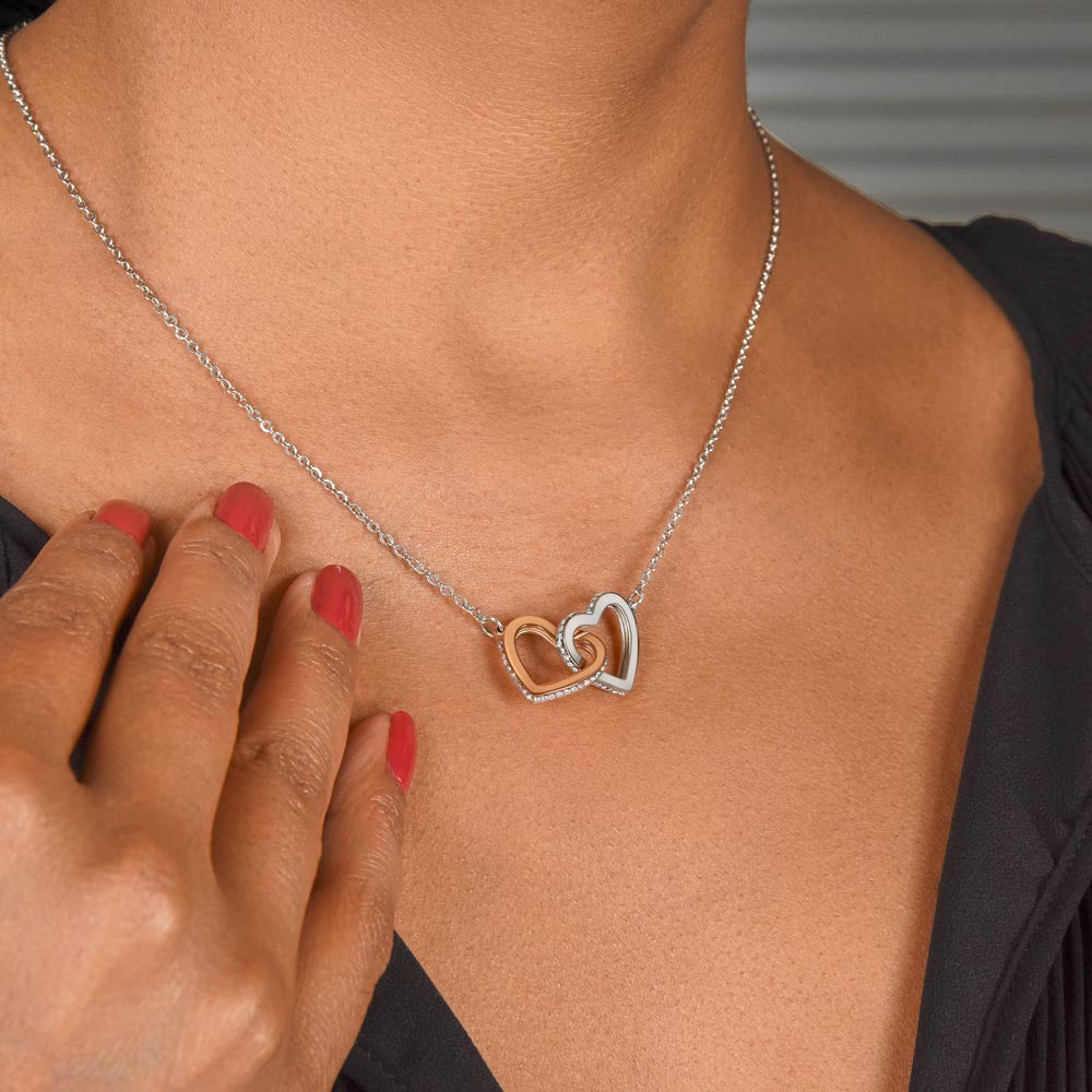 Woman wearing the interlocking hearts pendant necklace in 14K white gold finish with rose gold accents resting against her collarbone.