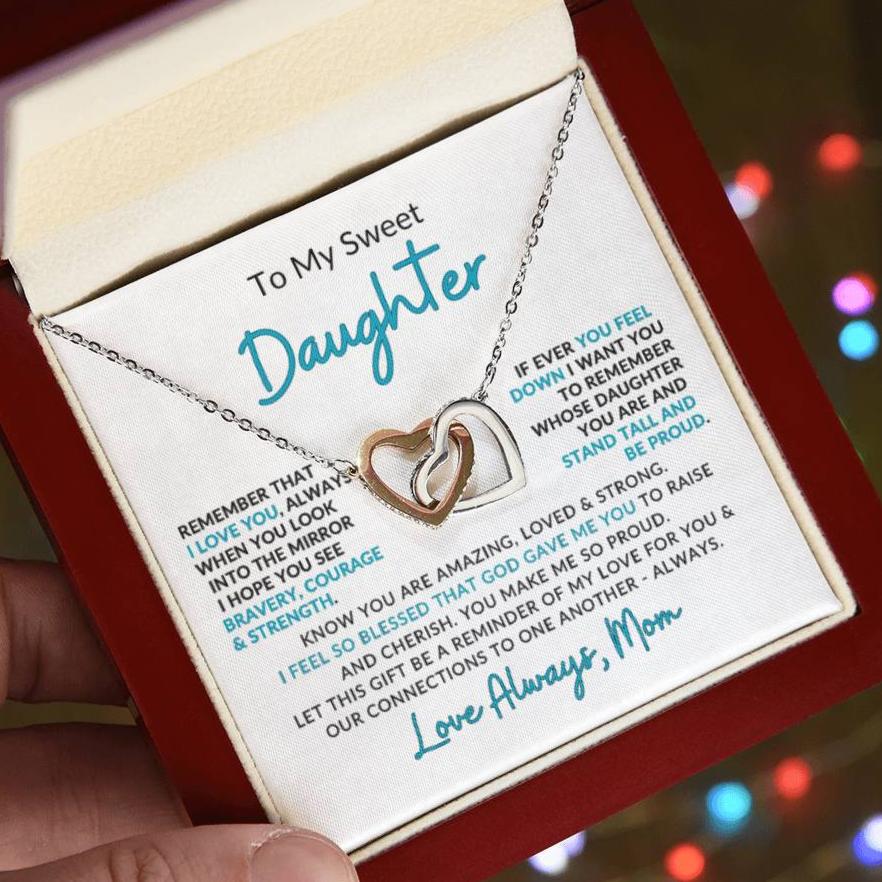 A necklace with two heart-shaped pendants, presented in a box with a personal message to a daughter from her mother.