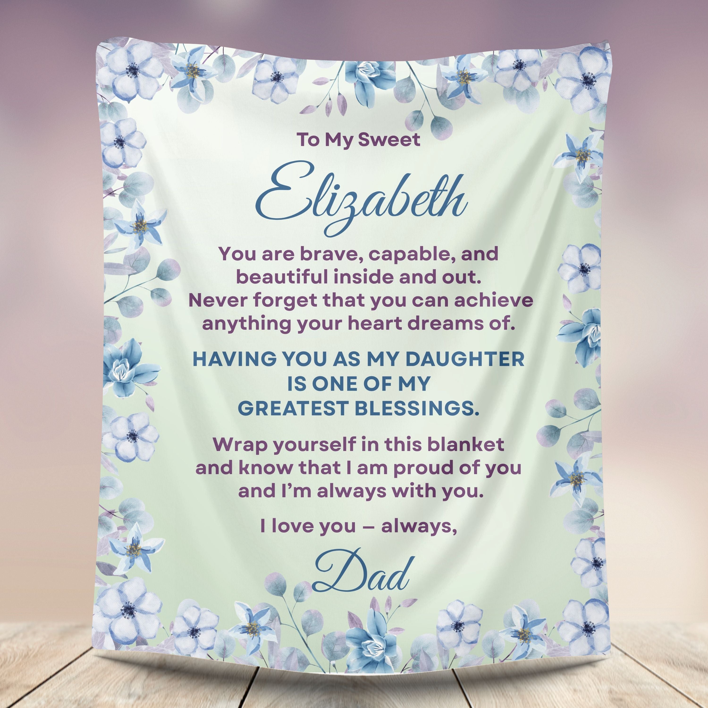  Personalized daughter blanket from Dad in soft sage with a blue floral design, shown hanging in a cozy room setting.