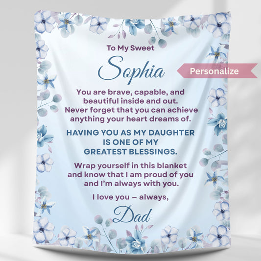 Personalized daughter blanket from Dad in cornflower with blue floral design, hanging against a white wall. 