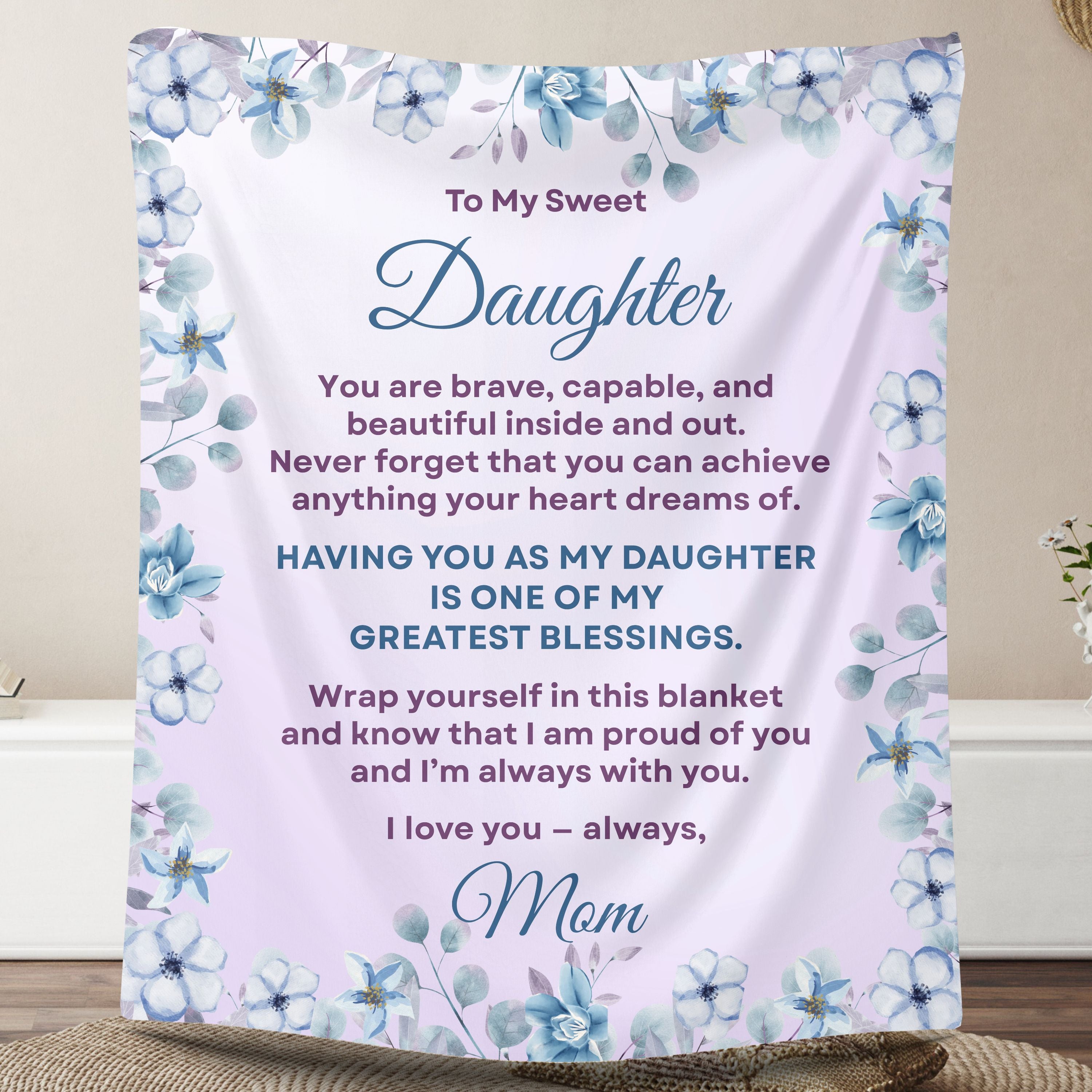 Personalized daughter blanket from Mom in Soft Lavender with a blue floral design, shown hanging in a cozy room setting.
