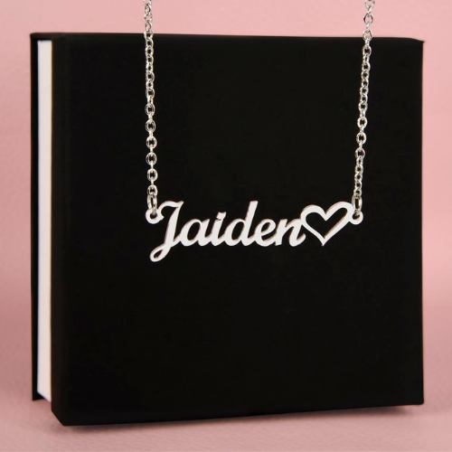 Silver personalized cursive name necklace with heart detail displayed in front of the standard black gift box.
