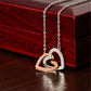 Close-up of the silver and rose gold interlocking hearts necklace resting in front of a luxury mahogany-style gift box, showcasing the pavé cubic zirconia crystals.
