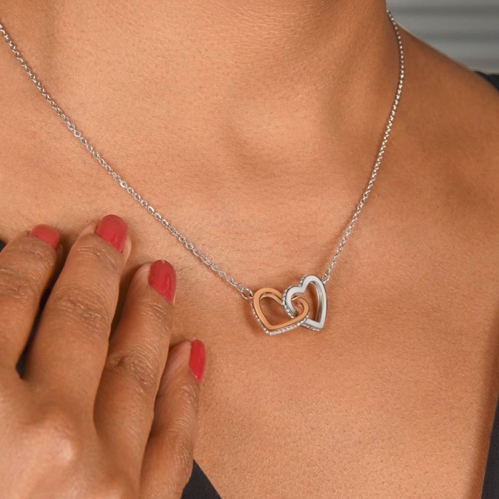 Close-up of a woman wearing a silver and rose gold interlocking hearts necklace with cubic zirconia crystals.